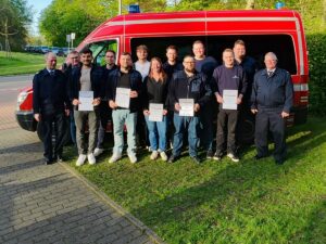 Gruppe von Personen mit Urkunden vor einem roten Einsatzfahrzeug